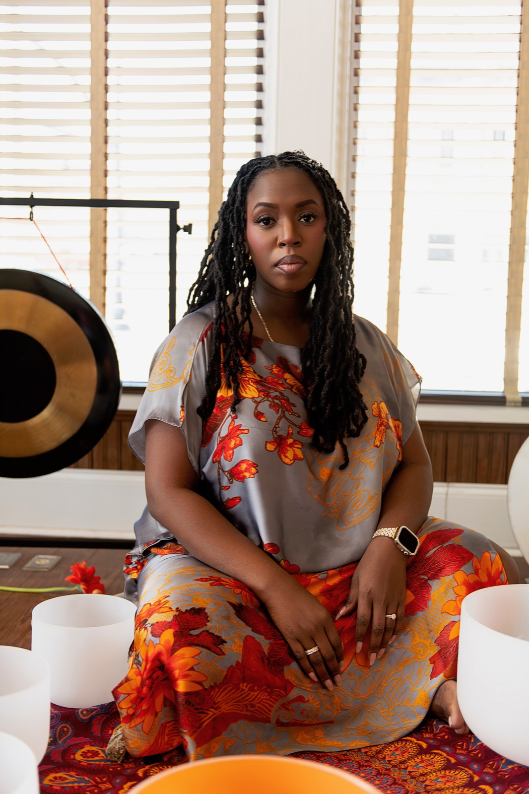 Portrait of Keyona McCarthy seated before a gong and crystal singing bowls