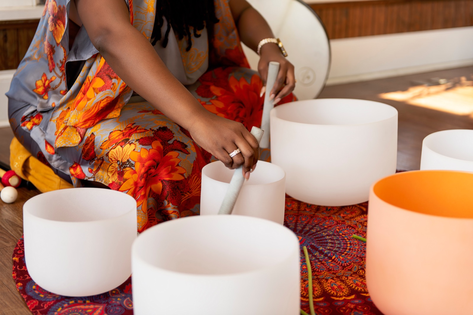 Keyona's hands playing crystal singing bowls arranged on a patterned cloth