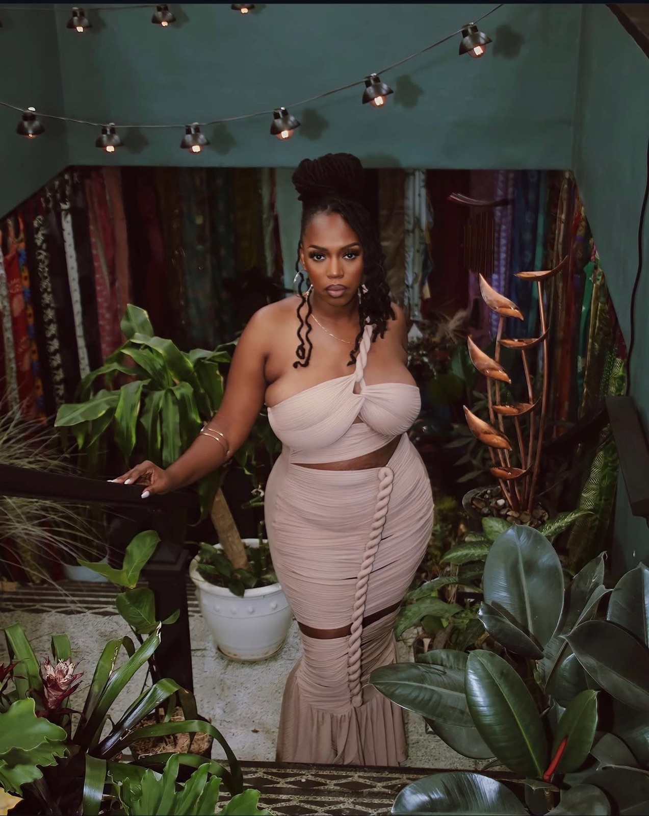 Keyona McCarthy standing among plants beneath string lights